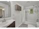Well-lit bathroom featuring a sink, wall cabinet, mirror and shower with white tiling and gray accents throughout at 1920 S Downing St, Denver, CO 80210