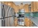 Compact kitchen boasts stainless steel appliances, natural wood cabinets, and green tile backsplash at 1920 S Downing St, Denver, CO 80210