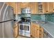 Compact kitchen boasts stainless steel appliances, natural wood cabinets, and green tile backsplash at 1920 S Downing St, Denver, CO 80210