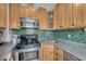 Compact kitchen boasts stainless steel appliances, natural wood cabinets, and green tile backsplash at 1920 S Downing St, Denver, CO 80210