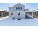 Rear view of a two-story house with a covered patio and snowy yard at 4911 Colorado River Dr, Firestone, CO 80504
