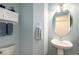 Powder room featuring blue walls, a pedestal sink, and a decorative cabinet with hanging towels at 735 Poppy Pl, Highlands Ranch, CO 80129