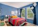 Cozy bedroom with blue walls, colorful bedding, and a view of the yard at 735 Poppy Pl, Highlands Ranch, CO 80129