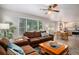 Open-concept living room with a comfortable sofa, ceiling fan, and views into the kitchen and a large, bright window at 735 Poppy Pl, Highlands Ranch, CO 80129