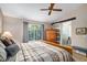 Main bedroom featuring an ensuite bathroom, a sliding barn door, ceiling fan, large window, and a wooden bedframe at 735 Poppy Pl, Highlands Ranch, CO 80129