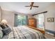 Main bedroom featuring a sliding barn door, ceiling fan, large window, and a wooden bedframe at 735 Poppy Pl, Highlands Ranch, CO 80129