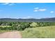 Scenic view overlooking rolling hills and lush greenery against a backdrop of distant mountains and blue skies at 735 Poppy Pl, Highlands Ranch, CO 80129