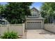 Two-car garage with traditional carriage doors, and gray siding, and a well-manicured lawn at 13025 Umatilla Ct, Denver, CO 80234