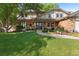 Charming two-story home with a lush green lawn, a brick facade, and a welcoming front porch with seating at 7830 W Friend Pl, Littleton, CO 80128