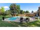 Backyard pool area with lounge chairs, patio furniture, and lush landscaping, creating a perfect relaxation space at 7830 W Friend Pl, Littleton, CO 80128