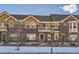 Charming townhome exterior with brick and siding, balcony, and a well-manicured front yard in a winter setting at 9234 Ridgegate Pkwy, Lone Tree, CO 80124