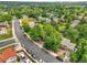 Aerial view of a neighborhood street lined with mature trees and well-maintained homes and lush lawns at 3224 S Dudley St, Lakewood, CO 80227