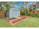 Outdoor storage shed with a metal roof, garden beds, and partial shade in backyard at 3224 S Dudley St, Lakewood, CO 80227