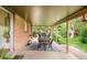 Inviting covered patio with brick siding features a dining table, stylish rug, and a tranquil view of the backyard at 12193 W New Mexico Pl, Lakewood, CO 80228