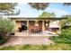 Charming covered patio with brick exterior includes a dining set and a swing, surrounded by lush landscaping at 12193 W New Mexico Pl, Lakewood, CO 80228