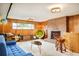 Retro-inspired living room with wood paneling, brick fireplace, and unique furnishings at 12193 W New Mexico Pl, Lakewood, CO 80228