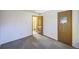 Empty bedroom features neutral walls and carpet tiles with a door leading to the hallway at 4474 S Vrain St, Denver, CO 80236