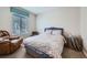 Cozy bedroom with a comfy armchair, window with blinds, and neutral decor at 14096 Roaring Fork, Broomfield, CO 80023