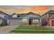 Charming two-story home with stone accents, manicured lawn, and an inviting covered front porch at sunset at 20795 Scenic Park Dr, Parker, CO 80138