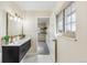 Bright bathroom with a double vanity, marble tile, a glass enclosed shower, and an open door to closet at 13232 W Jewell Cir, Lakewood, CO 80228