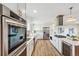 Open kitchen with modern appliances, white cabinets, stainless steel refrigerator, and hardwood flooring at 13232 W Jewell Cir, Lakewood, CO 80228