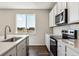 White kitchen features stainless appliances, tiled backsplash, and sink near a window at 14366 Heritage Dr, Mead, CO 80504