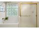 Bright bathroom featuring a glass block window above a soaking tub and gold-framed glass shower doors at 6321 Spotted Fawn Run, Littleton, CO 80125
