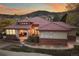 Charming single-Gathering home with a tile roof, stone accents, and manicured landscaping under a colorful sunset at 6321 Spotted Fawn Run, Littleton, CO 80125
