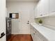 Well-lit laundry room with white cabinetry, a utility sink, and modern washer and dryer at 6321 Spotted Fawn Run, Littleton, CO 80125