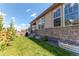 A backyard with a stone foundation for the house with a lawn and some greenery at 24197 E Ada Ave, Aurora, CO 80018