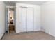 Spare bedroom featuring neutral carpet, closet with bi-fold doors, and a side view to a living space at 24197 E Ada Ave, Aurora, CO 80018