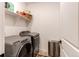 Well-lit laundry room boasts modern washer and dryer units with convenient shelving above at 24197 E Ada Ave, Aurora, CO 80018