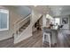 Modern living space featuring sleek stairs, wood floors, and an open layout to the kitchen and dining area at 10346 Uvalda Ave, Commerce City, CO 80022