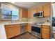Modern kitchen featuring stainless steel appliances, wood cabinets, and tile floors at 8791 Starwood Ln, Parker, CO 80134
