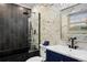 Modern bathroom featuring white marble walls, black shower, blue vanity, and a gold mirror at 3850 Hopi Dr, Sedalia, CO 80135