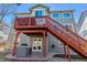Exterior of home featuring an elevated red deck and stairs leading down to a stone patio and outdoor grill area at 474 Rose Finch Cir, Highlands Ranch, CO 80129