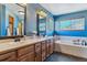 Blue bathroom features a double sink vanity, soaking tub, windows, and modern fixtures at 474 Rose Finch Cir, Highlands Ranch, CO 80129
