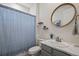 Cozy bathroom featuring a vanity with marble countertops, oval mirror and gray cabinets at 141 Back Nine Dr, Castle Pines, CO 80108