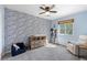 Stylish bedroom with a blue-themed accent wall, a ceiling fan and light neutral carpet and chair at 11777 Elizabeth Cir, Thornton, CO 80233