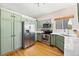Spacious kitchen with stainless steel appliances, light green cabinetry, and hardwood floors bathed in natural light at 11777 Elizabeth Cir, Thornton, CO 80233