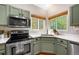 A close-up view of a kitchen corner featuring stainless steel appliances and verdant outside views through two windows at 11777 Elizabeth Cir, Thornton, CO 80233