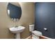 Stylish powder room featuring a pedestal sink, round mirror, and modern fixtures at 581 N Flat Rock Cir, Aurora, CO 80018