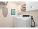 Functional laundry room with white appliances, ample cabinet space and an ironing board at 23813 Broadmoor Dr, Parker, CO 80138