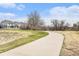 A paved walking path winds through a green space with trees and homes in the background at 23813 Broadmoor Dr, Parker, CO 80138