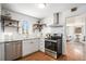 Modern kitchen featuring stainless steel appliances, white cabinetry, and open shelving at 865 S Dale Ct, Denver, CO 80219