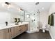 Modern bathroom with dual sink vanity, large mirror, and glass-enclosed shower with marble surround at 1385 N King St, Denver, CO 80204