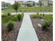 Landscaped front yard featuring a stone pathway, lush grass, and well-maintained greenery, with neighborhood homes in the background at 5126 Buckwheat Rd, Brighton, CO 80640
