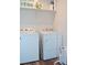 Functional laundry room with modern washer and dryer, shelf storage for supplies, and ample space at 5126 Buckwheat Rd, Brighton, CO 80640