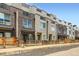 Modern townhomes with mixed brick and siding exteriors, complemented by wooden fences and rooftop decks against a clear blue sky at 3520 W Conejos Pl # 11, Denver, CO 80204