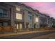 Dusk view of modern townhomes featuring brick and siding exteriors, wooden fences, and rooftop decks under a vibrant, pink-tinged sky at 3520 W Conejos Pl # 11, Denver, CO 80204